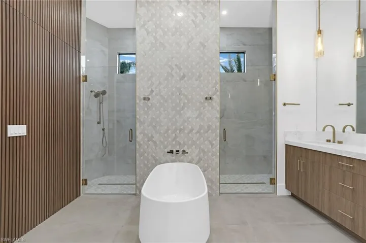 Full bath featuring vanity, a shower stall, a freestanding bath, and plenty of natural light
