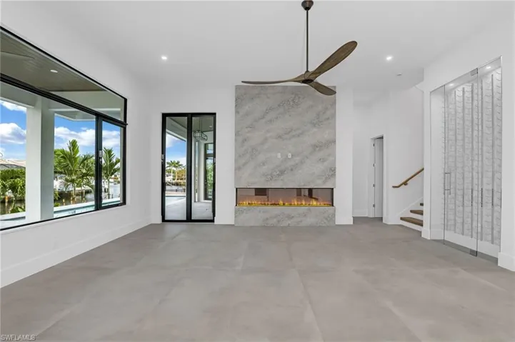 Unfurnished living room with recessed lighting, concrete flooring, a high end fireplace, stairs, and a ceiling fan