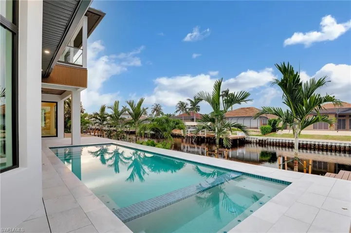 View of pool featuring a water view, a pool with connected hot tub, and a patio