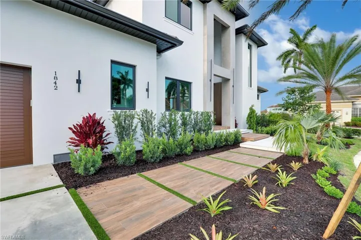 View of front of house with stucco siding, driveway, a garage, and a front lawn