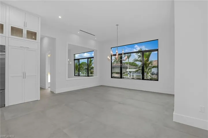 Unfurnished living room with a chandelier, concrete floors, and recessed lighting
