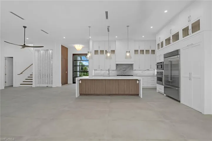 Kitchen featuring open floor plan, backsplash, concrete floors, light countertops, and appliances with stainless steel finishes