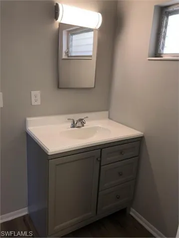 Bathroom with vanity, wood finished floors, and baseboards