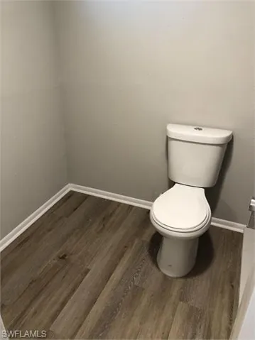 Bathroom featuring baseboards, toilet, and wood finished floors