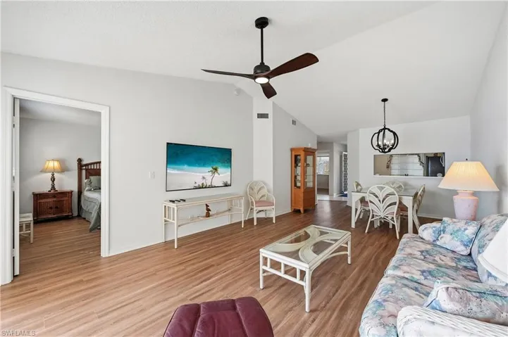 Living room with a chandelier, wood finished floors, lofted ceiling, and ceiling fan