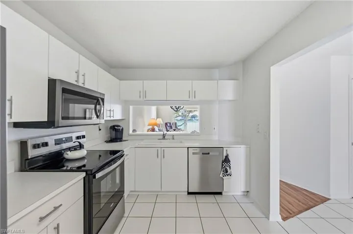 Kitchen featuring stainless steel appliances, light countertops, white cabinets, and light tile patterned floors