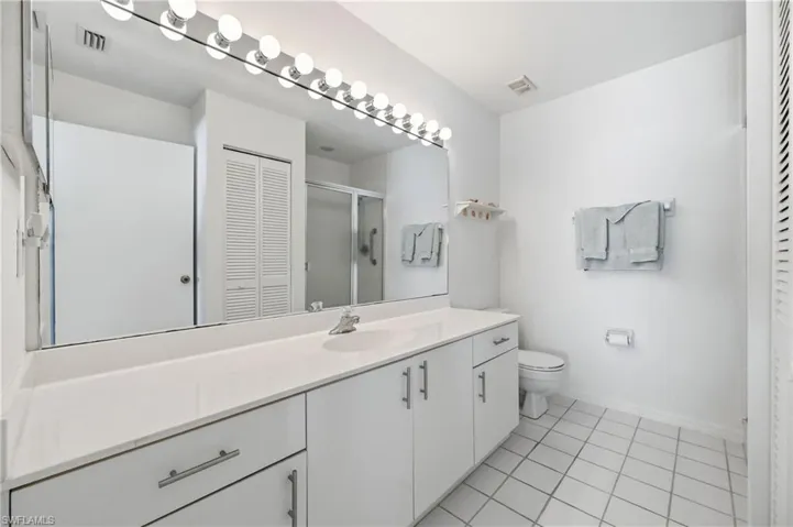Bathroom with a closet, vanity, a stall shower, and light tile patterned floors