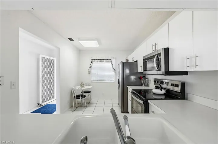 Kitchen featuring stainless steel appliances, light countertops, white cabinetry, and light tile patterned floors