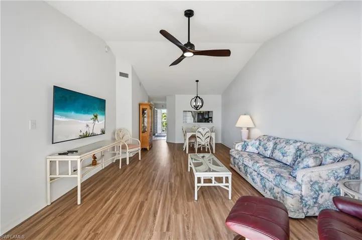 Living room with wood finished floors, lofted ceiling, and ceiling fan