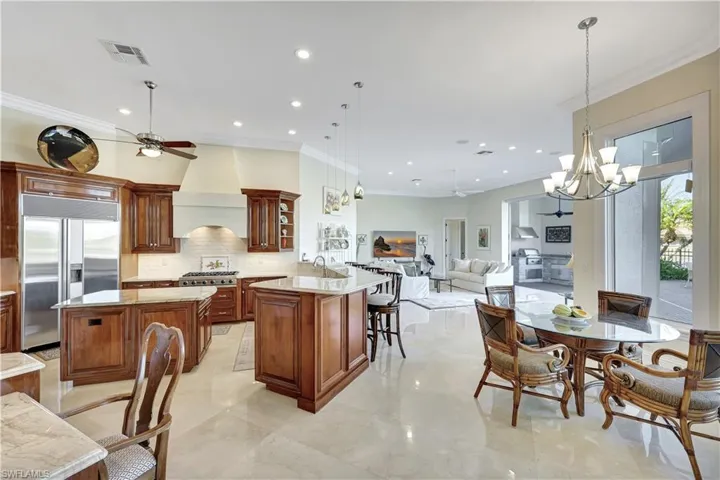 Kitchen with ornamental molding, decorative light fixtures, light stone countertops, backsplash, and recessed lighting