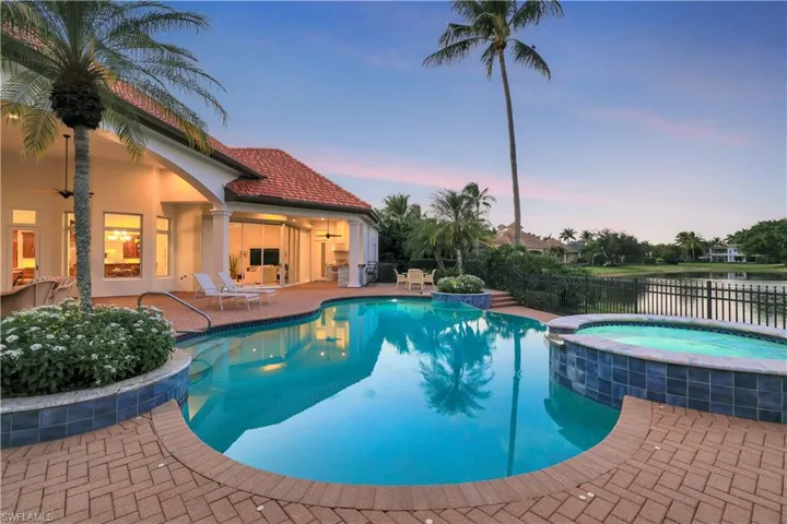 Pool at dusk with a patio area, a pool with connected hot tub, and a ceiling fan