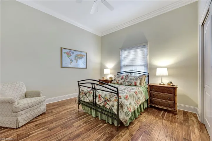 Bedroom with crown molding, wood finished floors, and ceiling fan