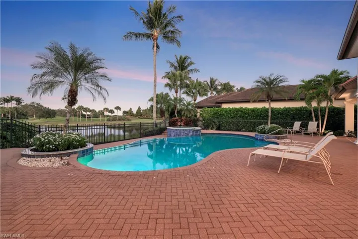 View of pool with a patio, a water view, and a pool with connected hot tub