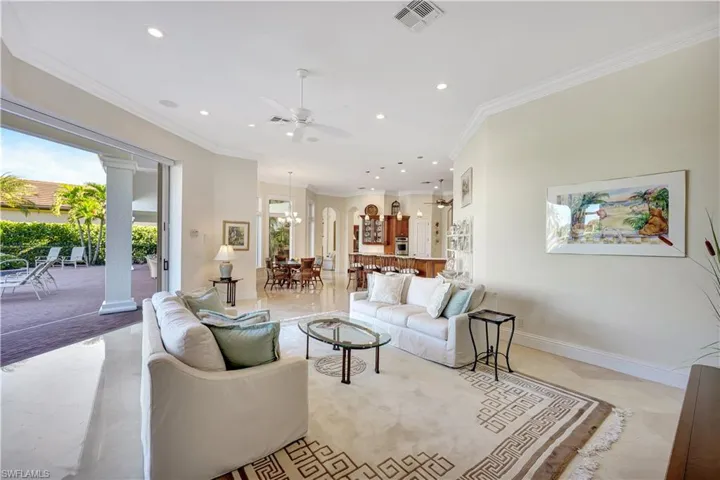 Living area with crown molding, recessed lighting, decorative columns, a ceiling fan, and a chandelier