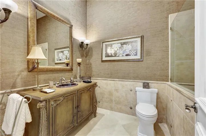 Bathroom with vanity, tile walls, wallpapered walls, and wainscoting