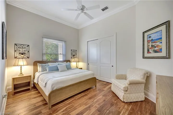 Bedroom with ornamental molding, wood finished floors, a closet, and ceiling fan