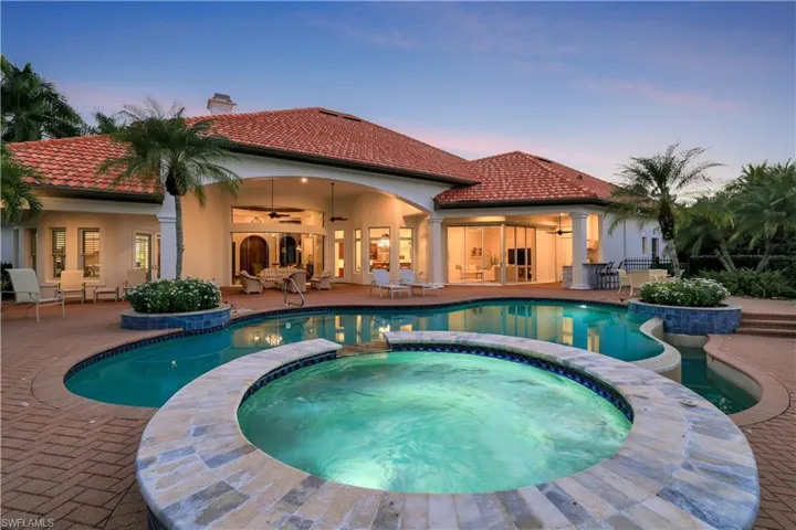 Pool at dusk featuring a ceiling fan, a patio, and a pool with connected hot tub