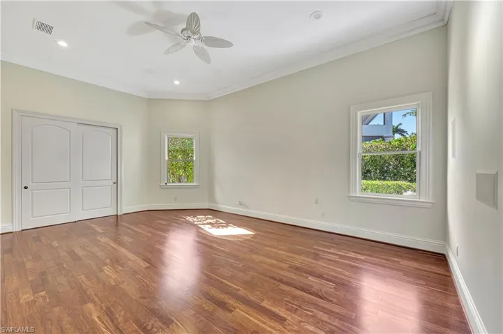 Unfurnished bedroom featuring crown molding, wood finished floors, a ceiling fan, a closet, and recessed lighting