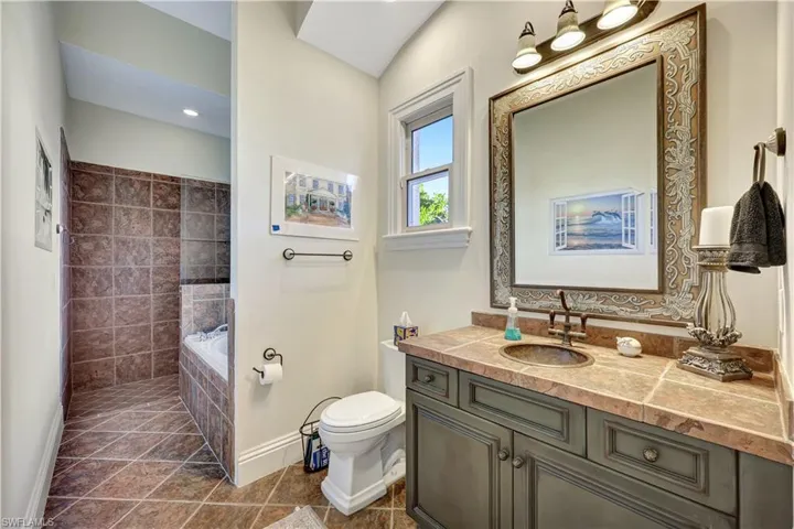 Full bath featuring a garden tub, vanity, dark tile patterned floors, and a tile shower