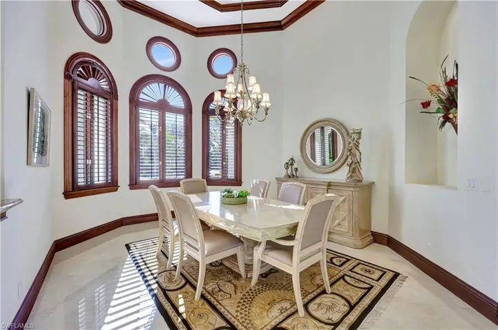 Dining area with ornamental molding, a high ceiling, and a chandelier
