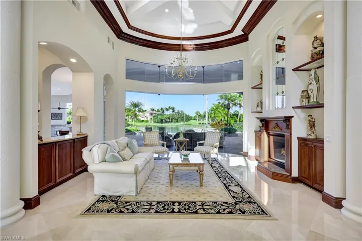 Living area featuring a high ceiling, arched walkways, ornamental molding, recessed lighting, and a chandelier