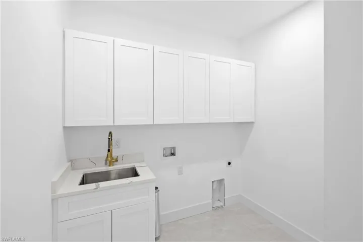 Laundry area with electric dryer hookup, hookup for a washing machine, sink, and cabinets