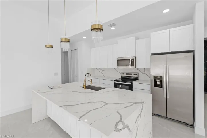 Kitchen featuring sink, backsplash, pendant lighting, a kitchen island with sink, and appliances with stainless steel finishes