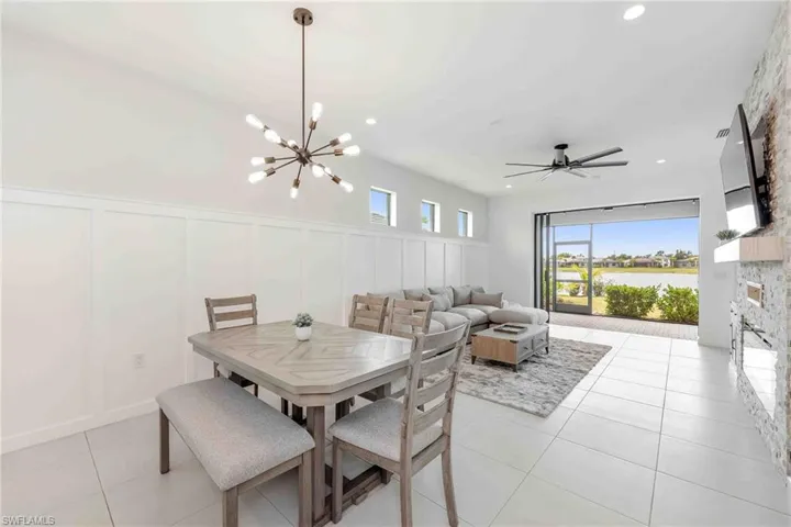 Dining room with a decorative wall, light tile patterned floors, a wainscoted wall, and recessed lighting