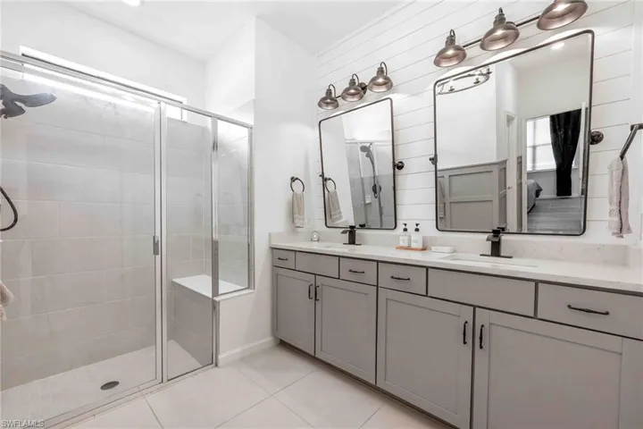 Bathroom with a sink, tile patterned flooring, a shower stall, and double vanity
