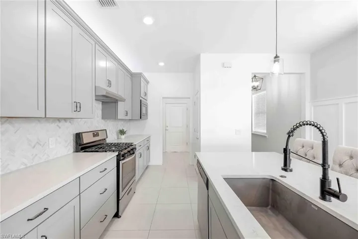 Kitchen featuring gray cabinets, a sink, and appliances with stainless steel finishes