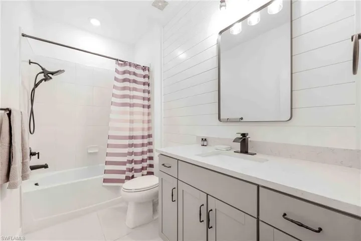 Bathroom featuring vanity, visible vents, toilet, shower / tub combo with curtain, and tile patterned floors