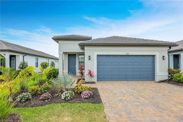 Prairie-style home featuring a tiled roof, an attached garage, decorative driveway, and stucco siding