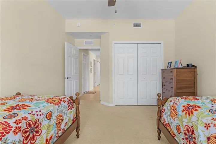 Bedroom featuring light colored carpet, ceiling fan, and a closet