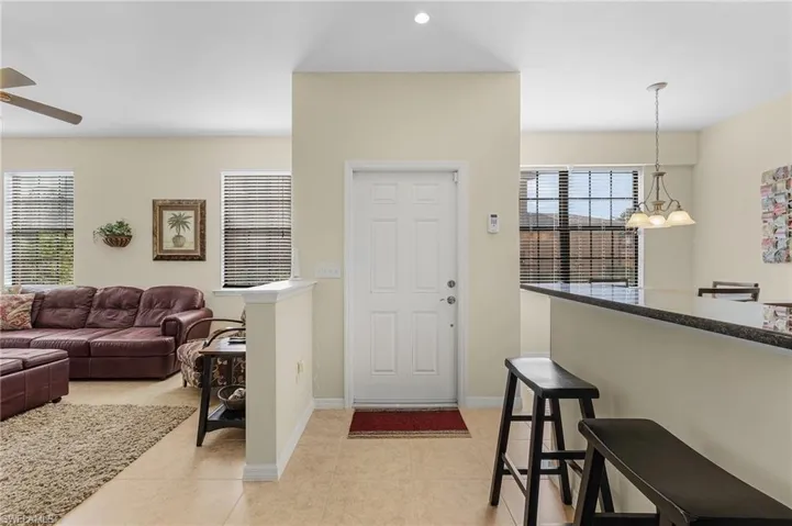 Tiled foyer entrance with ceiling fan with notable chandelier