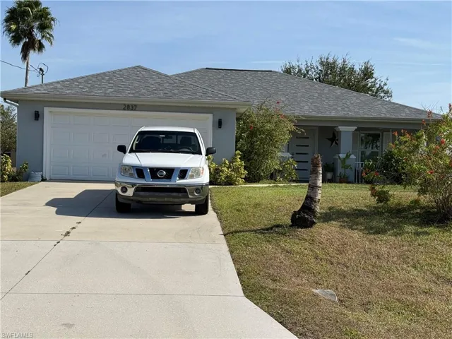 Ranch-style house featuring concrete driveway, roof with shingles, a garage, and stucco siding