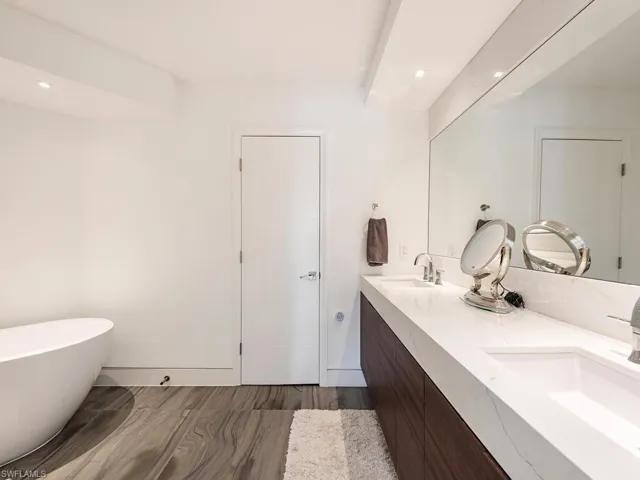 Bathroom featuring a sink, a soaking tub, wood finished floors, and double vanity