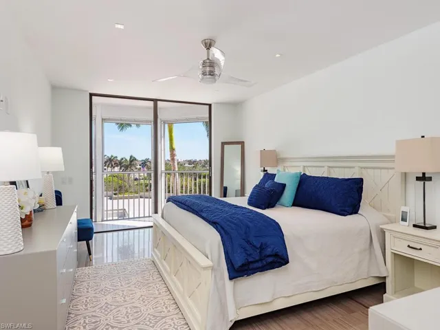 Bedroom featuring a wall of windows, access to exterior, wood finished floors, and a ceiling fan
