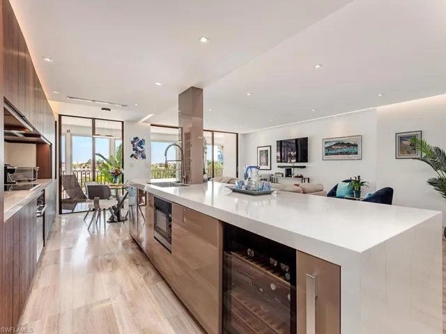 Kitchen with a spacious island, a sink, wine cooler, black microwave, and modern cabinets