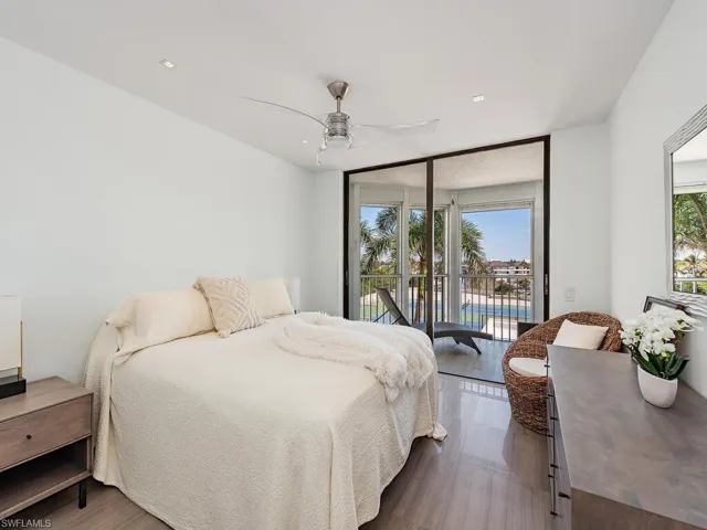 Bedroom with a wall of windows, wood finished floors, ceiling fan, and access to outside
