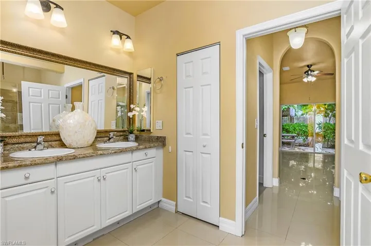 Bathroom with ceiling fan, dual vanity, and tile patterned flooring