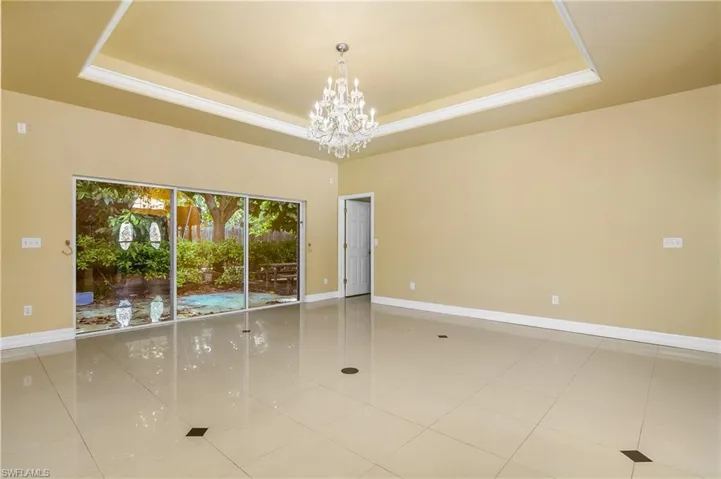 Tiled spare room featuring an inviting chandelier and a tray ceiling