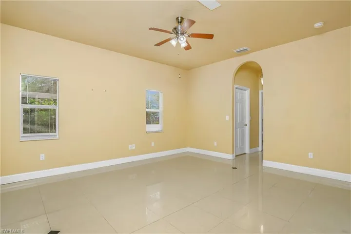 Spare room with ceiling fan, light tile patterned flooring, and a healthy amount of sunlight