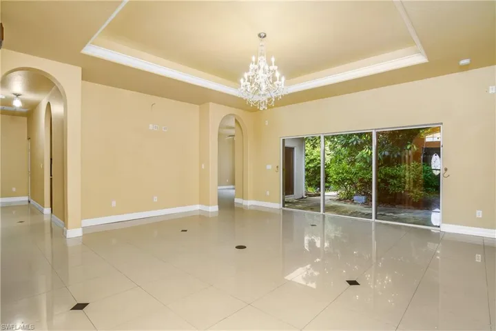 Unfurnished room with a notable chandelier, a raised ceiling, and tile patterned floors