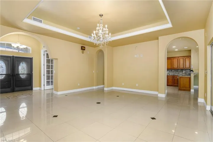 Tiled entrance foyer with a chandelier and a tray ceiling