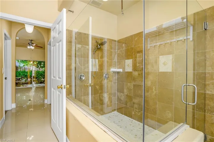 Bathroom with an enclosed shower, ceiling fan, and tile patterned flooring
