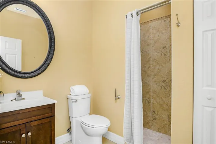 Bathroom featuring a shower with curtain, toilet, and vanity