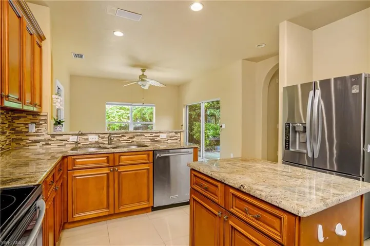 Kitchen with ceiling fan, stainless steel appliances, light tile patterned flooring, tasteful backsplash, and sink