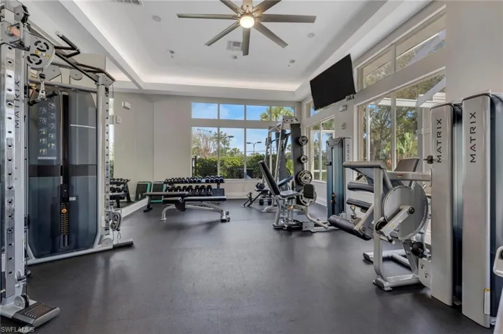 Exercise room with a ceiling fan and a tray ceiling