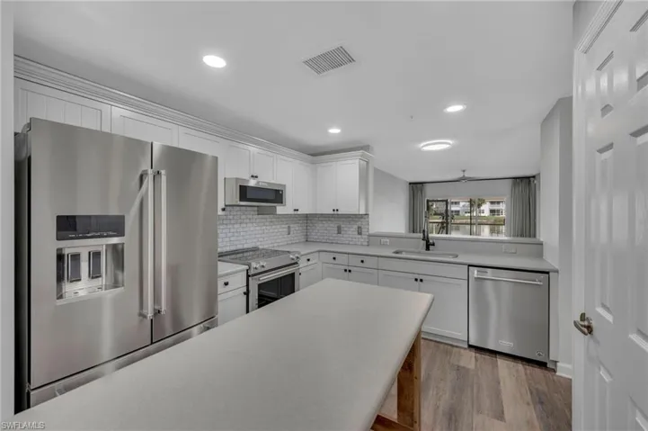 Kitchen with high quality appliances, white cabinetry, light wood-style flooring, recessed lighting, and tasteful backsplash