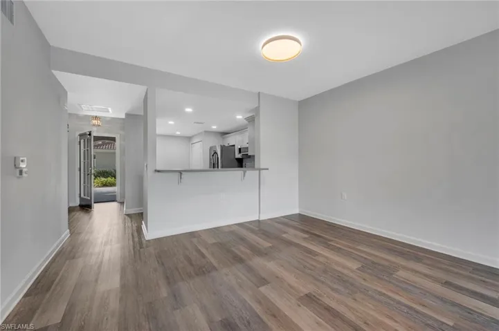 Unfurnished living room featuring dark wood-style flooring and recessed lighting